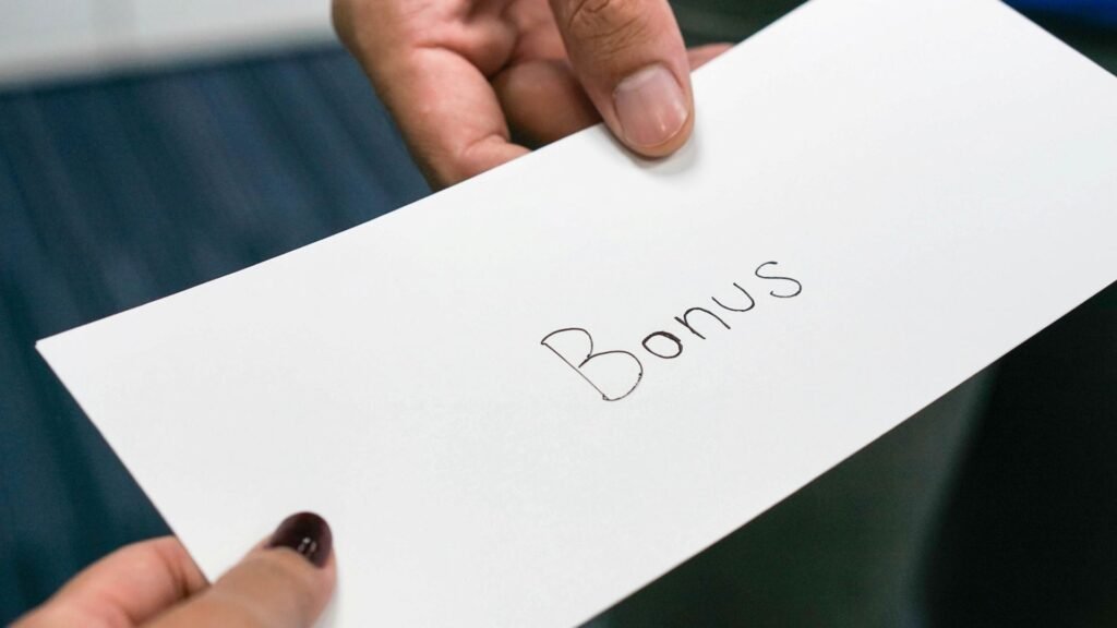 Enveloppe « Bonus » remise de main à main, illustrant le welcome bonus lors d’un changement d’entreprise